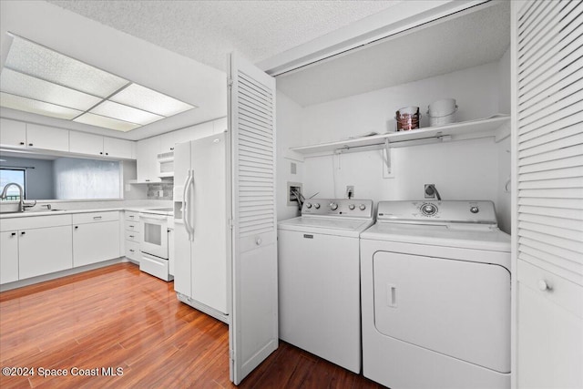 laundry room featuring washer and clothes dryer, sink, light hardwood / wood-style floors, and a textured ceiling