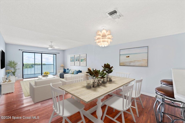 dining room with wood-type flooring, ceiling fan, and a textured ceiling