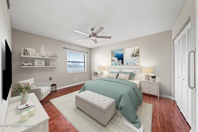 bedroom featuring dark wood-type flooring, ceiling fan, a textured ceiling, and a closet