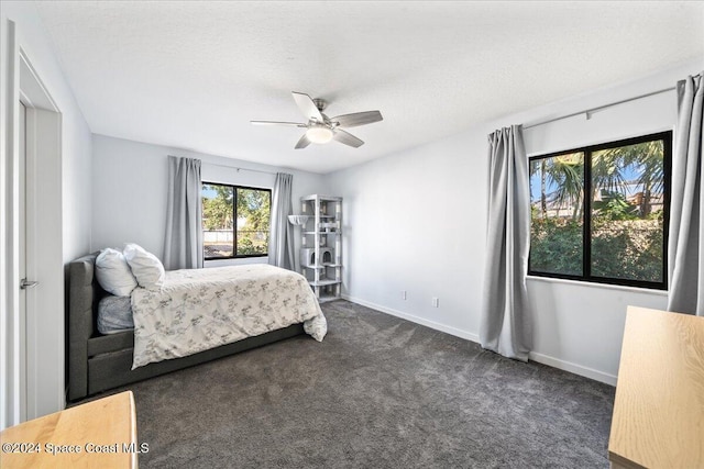 bedroom with dark colored carpet, a textured ceiling, and ceiling fan