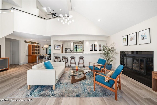 living room featuring beam ceiling, an inviting chandelier, high vaulted ceiling, and light hardwood / wood-style flooring