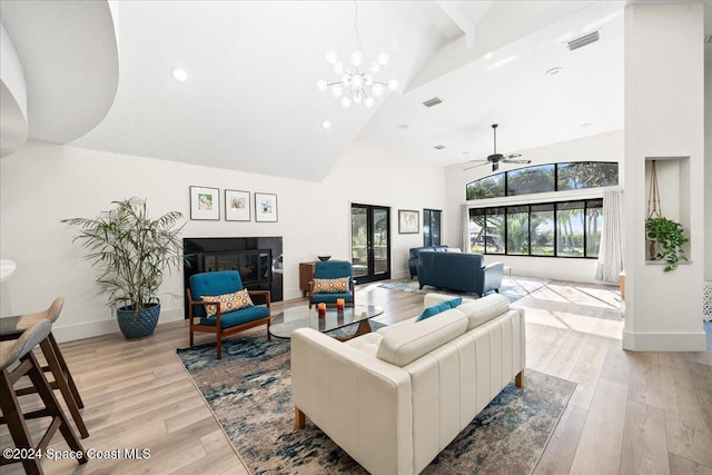 living room with ceiling fan with notable chandelier, high vaulted ceiling, and light hardwood / wood-style flooring