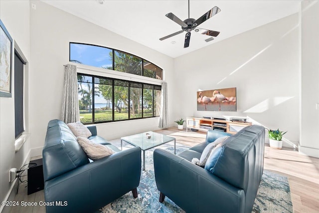 living room with ceiling fan, high vaulted ceiling, and wood-type flooring