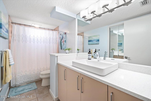 bathroom with tile patterned flooring, vanity, toilet, and a textured ceiling