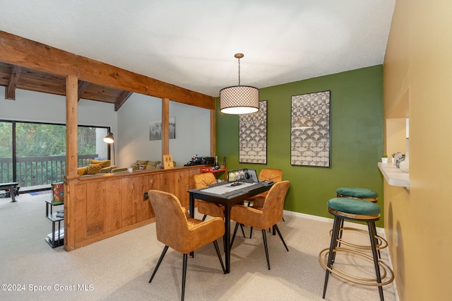 dining room featuring beam ceiling and light colored carpet