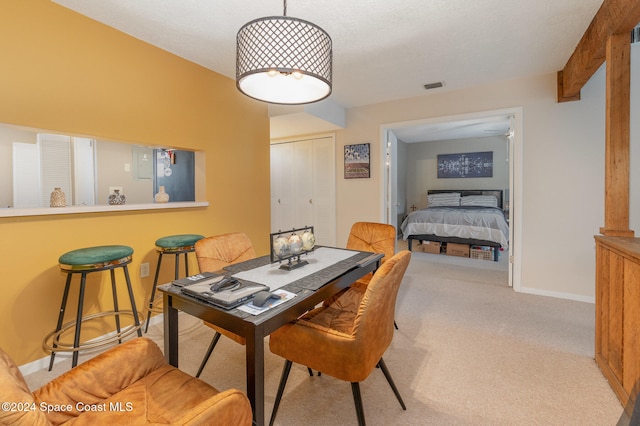 carpeted dining area with beam ceiling and a textured ceiling