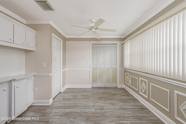 204 Queens Ct, Satellite Beach, FL 32937 - unfurnished dining area featuring ceiling fan, a textured ceiling, light wood-type flooring, ornamental molding, and baseboards