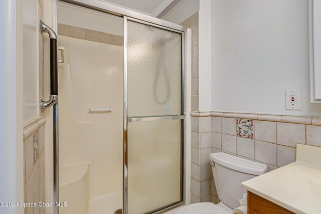 204 Queens Ct, Satellite Beach, FL 32937 - full bath featuring vanity, toilet, a shower stall, a wainscoted wall, and tile walls