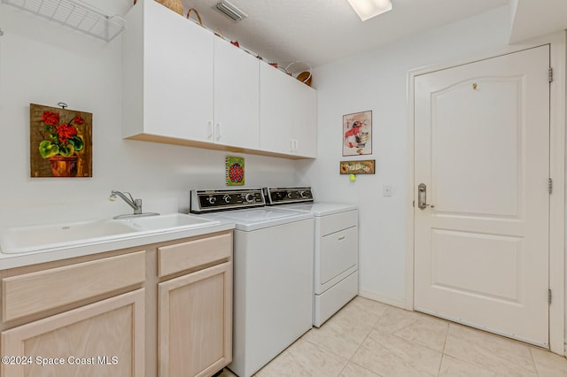 clothes washing area with cabinets, washer and dryer, and sink