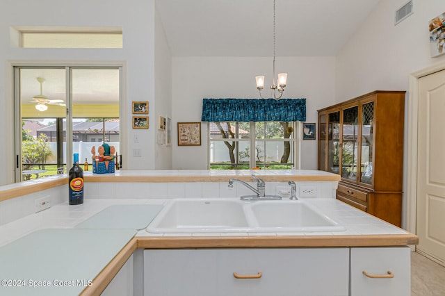 kitchen with pendant lighting, lofted ceiling, sink, and white cabinets