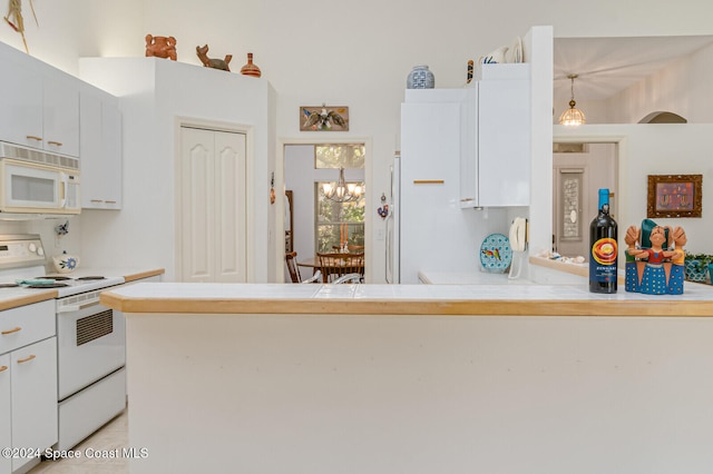 kitchen featuring pendant lighting, a chandelier, stove, and white cabinets