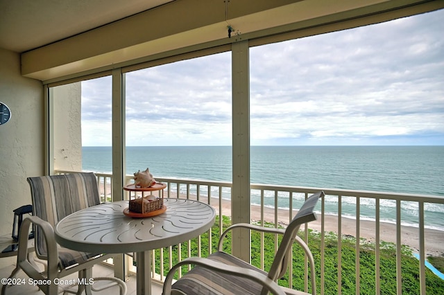 sunroom featuring a beach view and a water view