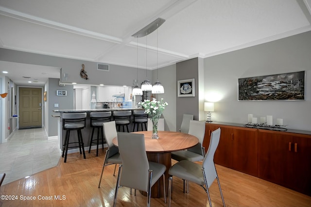 dining space featuring light wood-type flooring and coffered ceiling