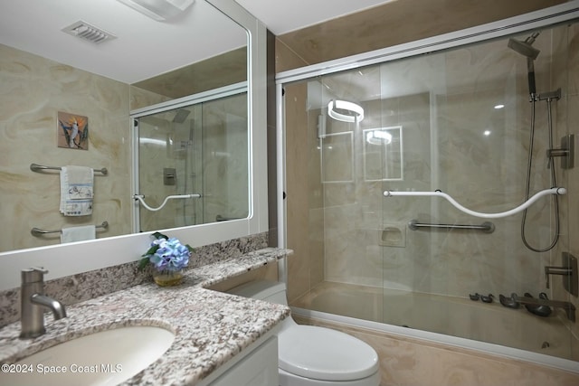 full bathroom featuring toilet, vanity, and combined bath / shower with glass door