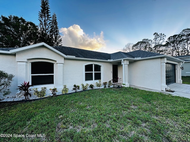 single story home featuring a garage and a lawn