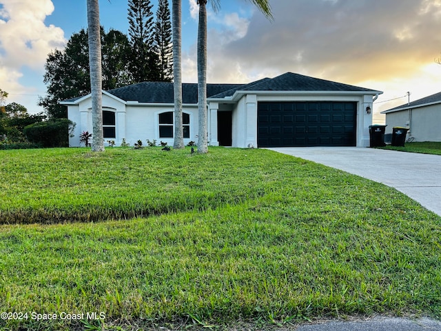 ranch-style house with a garage and a lawn