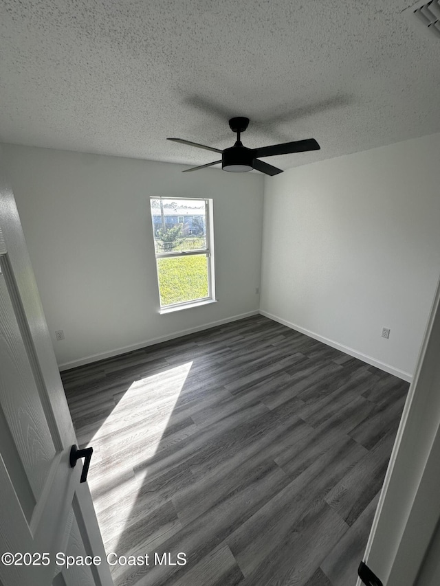 empty room featuring a textured ceiling, ceiling fan, and dark wood-type flooring