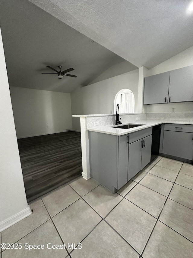 kitchen with kitchen peninsula, ceiling fan, sink, gray cabinets, and lofted ceiling