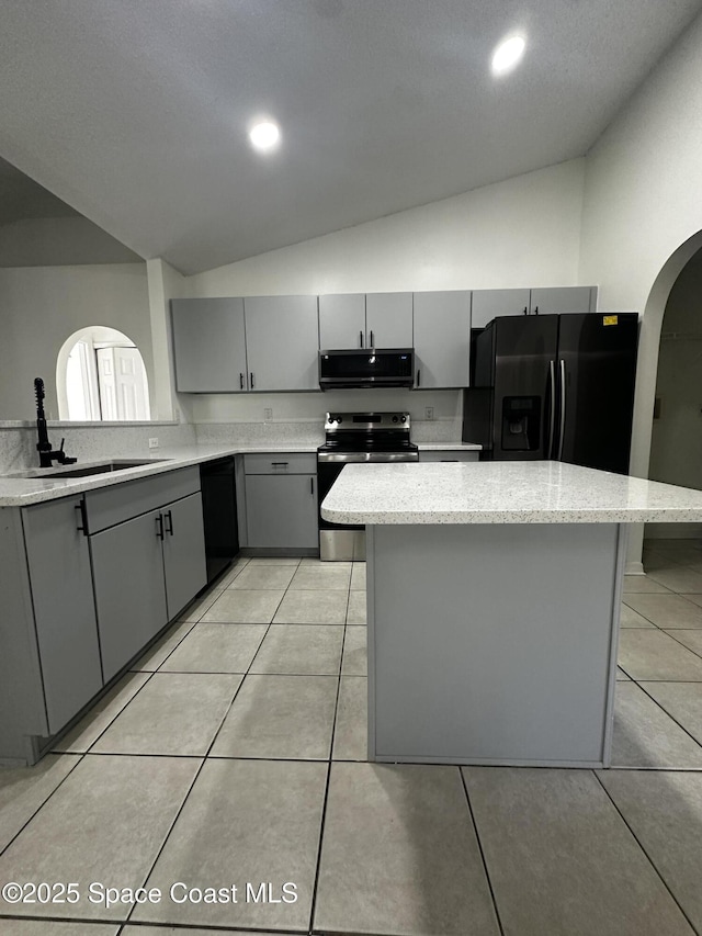 kitchen featuring sink, lofted ceiling, gray cabinets, a kitchen island, and black appliances