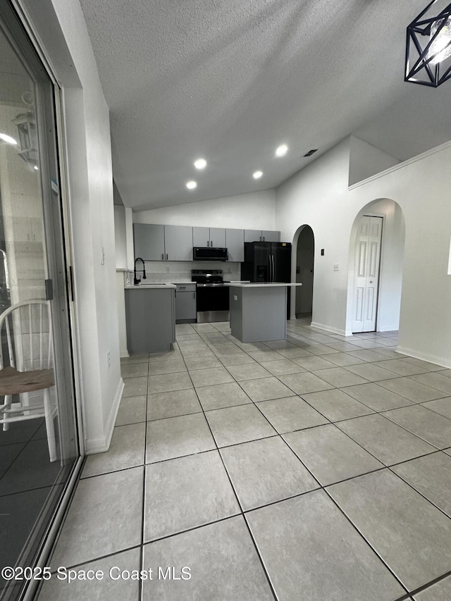 kitchen with gray cabinetry, black refrigerator with ice dispenser, stainless steel electric stove, a textured ceiling, and a kitchen island