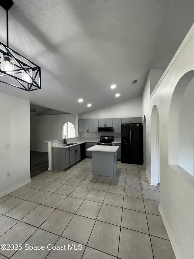 kitchen featuring stainless steel range with electric stovetop, black fridge, sink, gray cabinets, and a kitchen island