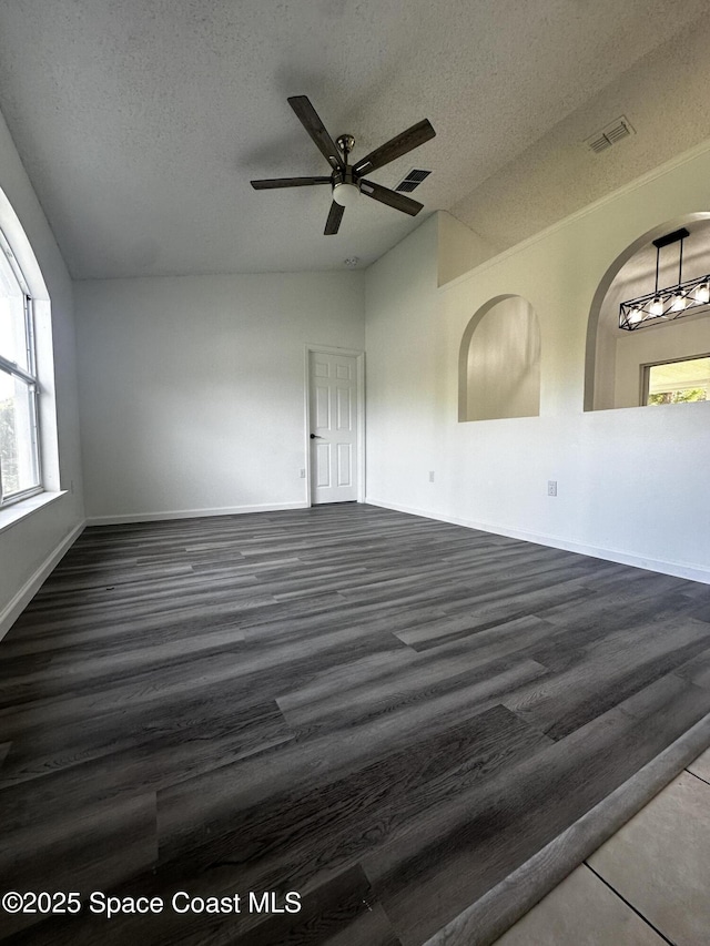 spare room featuring ceiling fan, dark hardwood / wood-style floors, lofted ceiling, and a textured ceiling