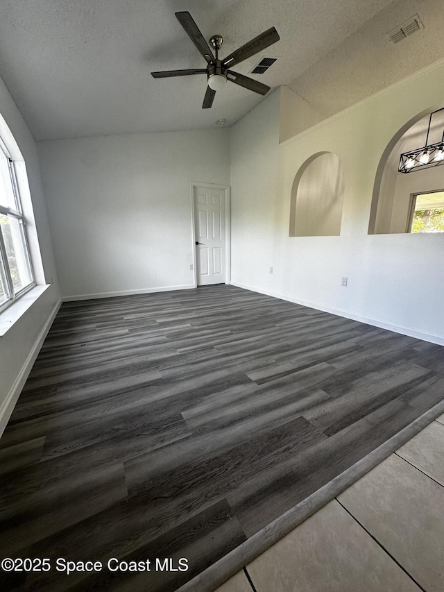 empty room with ceiling fan, a textured ceiling, a wealth of natural light, and vaulted ceiling