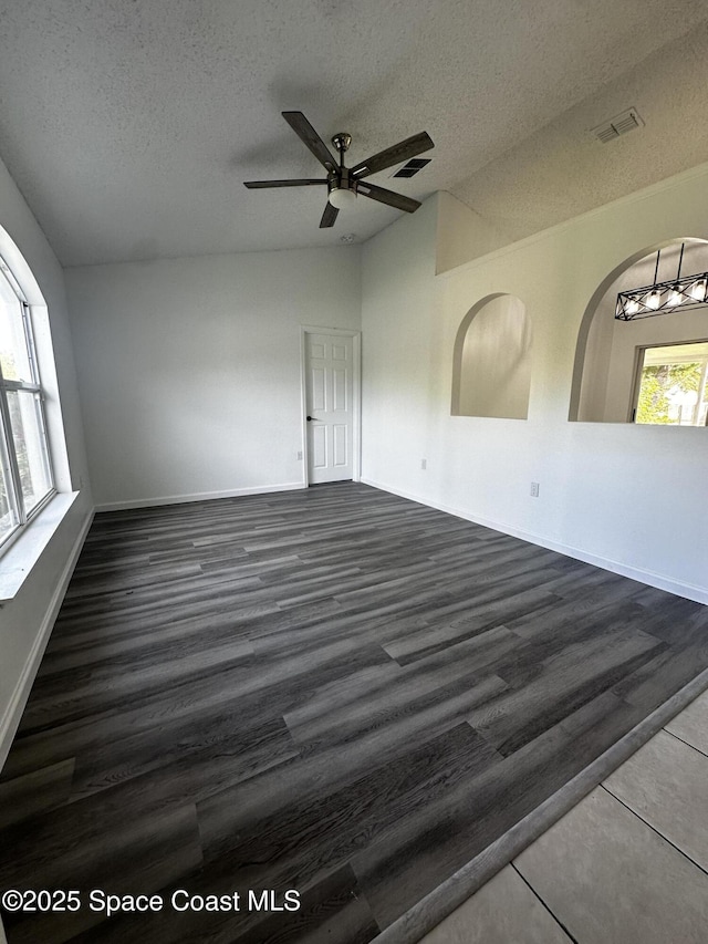 spare room featuring a textured ceiling, dark hardwood / wood-style floors, a wealth of natural light, and ceiling fan