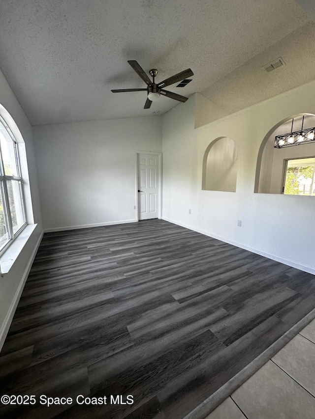 unfurnished room featuring a textured ceiling, dark wood-type flooring, ceiling fan, and lofted ceiling