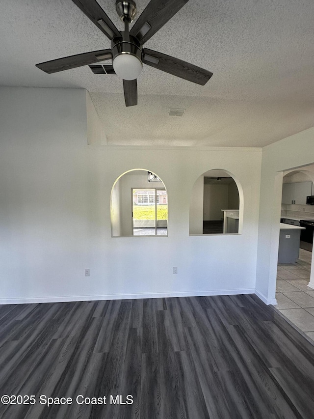 empty room with ceiling fan, a textured ceiling, and dark wood-type flooring