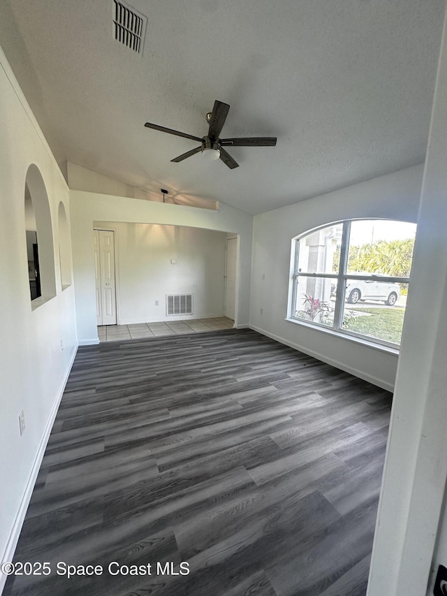 spare room with a textured ceiling, dark hardwood / wood-style flooring, ceiling fan, and lofted ceiling