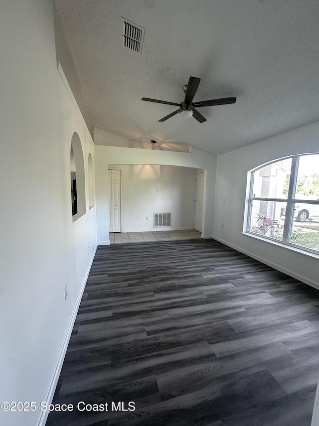 unfurnished living room with dark hardwood / wood-style flooring, a textured ceiling, vaulted ceiling, and ceiling fan