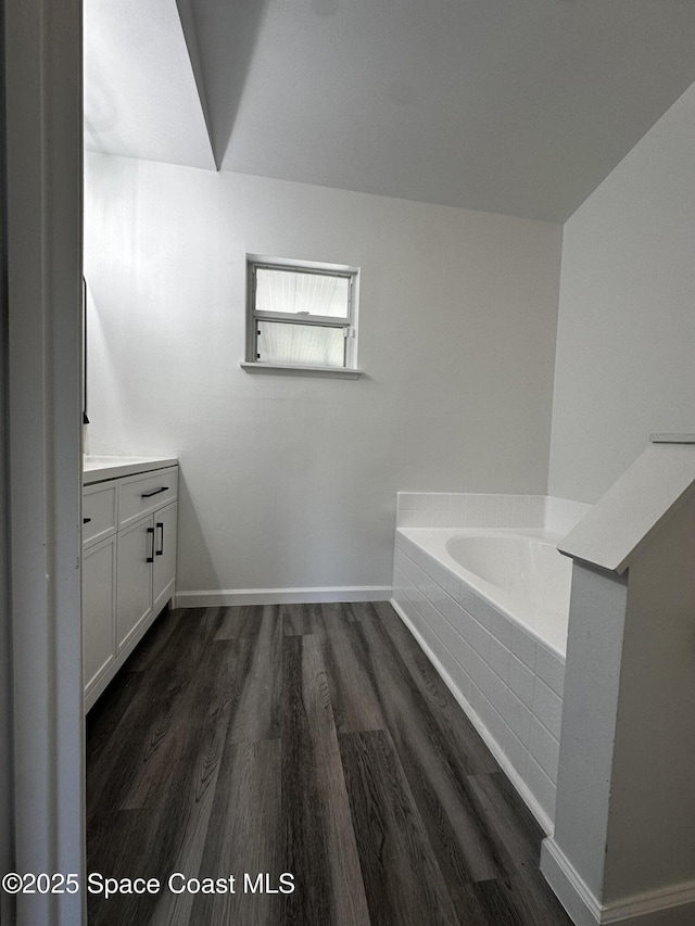 bathroom with vanity, wood-type flooring, and a tub to relax in