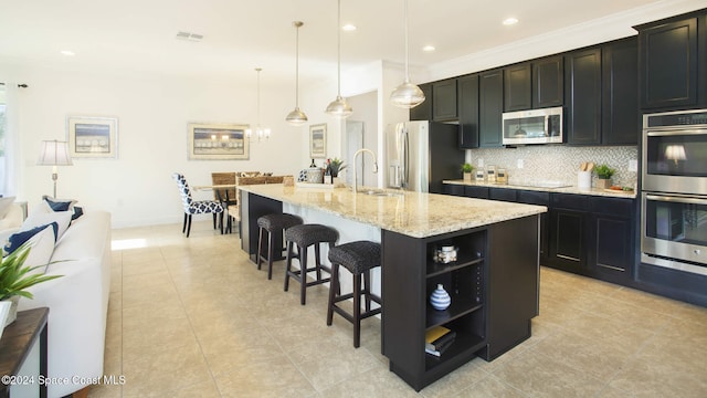 542 Acacia Ave, Sebastian, FL 32958 - kitchen with appliances with stainless steel finishes, decorative backsplash, a breakfast bar, a kitchen island with sink, and a sink