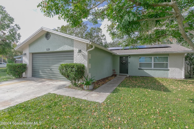 ranch-style home with a garage, a front yard, and solar panels