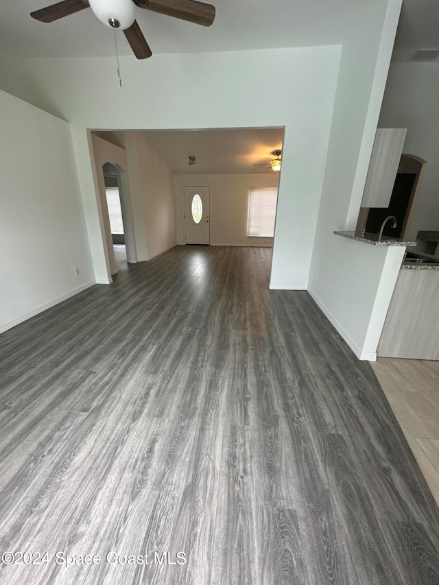 unfurnished living room with ceiling fan and dark hardwood / wood-style flooring