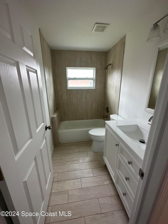 full bathroom featuring tiled shower / bath combo, toilet, and vanity