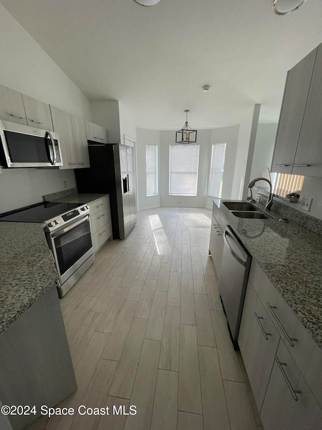 kitchen with pendant lighting, sink, light hardwood / wood-style flooring, stone countertops, and stainless steel appliances