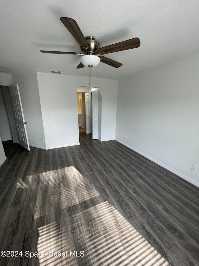 interior space with a textured ceiling, dark hardwood / wood-style flooring, and ceiling fan