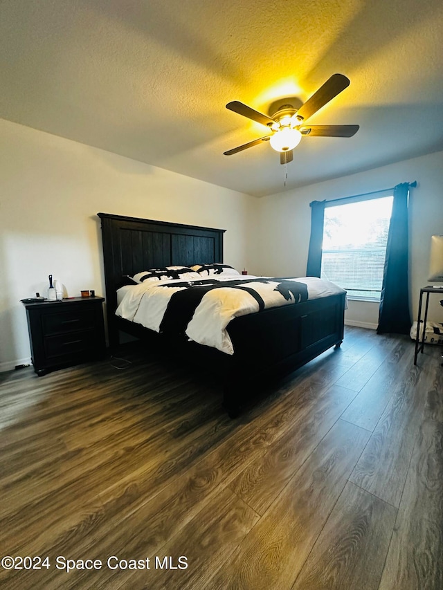 bedroom with ceiling fan, dark hardwood / wood-style flooring, and a textured ceiling