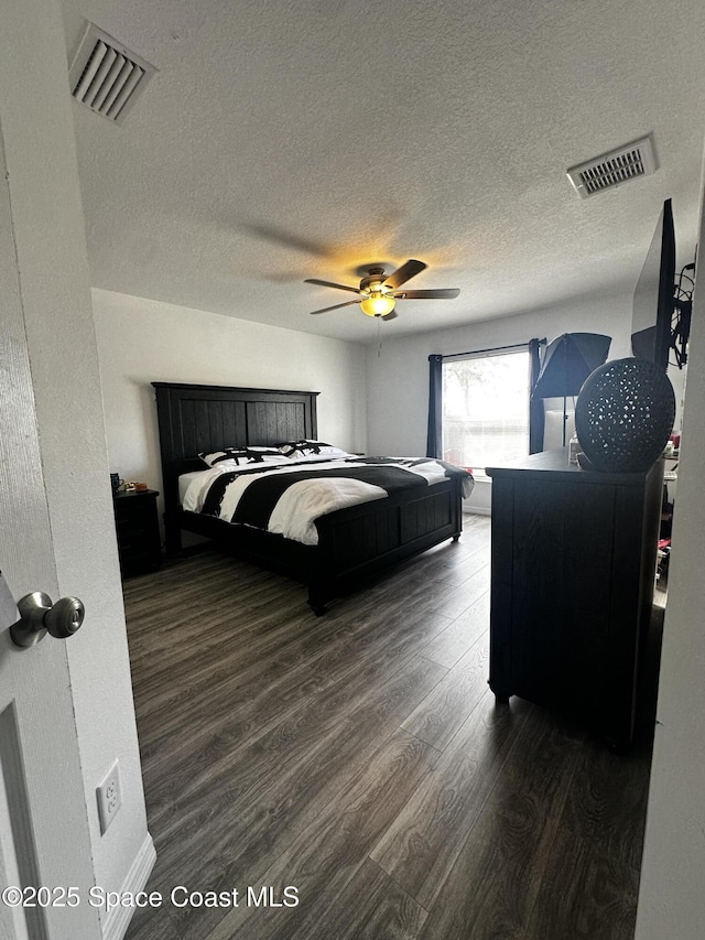 bedroom with a textured ceiling, dark hardwood / wood-style flooring, and ceiling fan