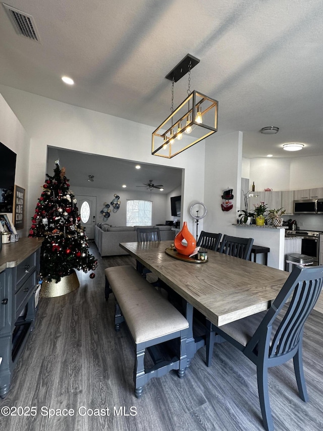 dining space featuring a textured ceiling, dark wood-type flooring, and ceiling fan with notable chandelier