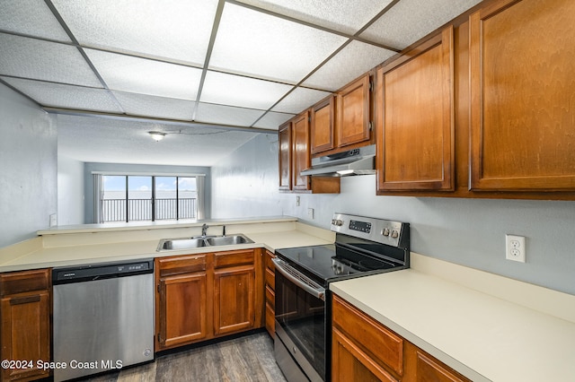 kitchen with kitchen peninsula, a drop ceiling, stainless steel appliances, sink, and dark hardwood / wood-style floors