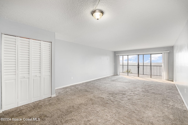 unfurnished bedroom with carpet flooring, a closet, a textured ceiling, and access to outside