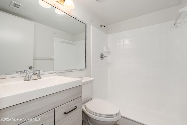 bathroom with toilet, vanity, and tiled shower