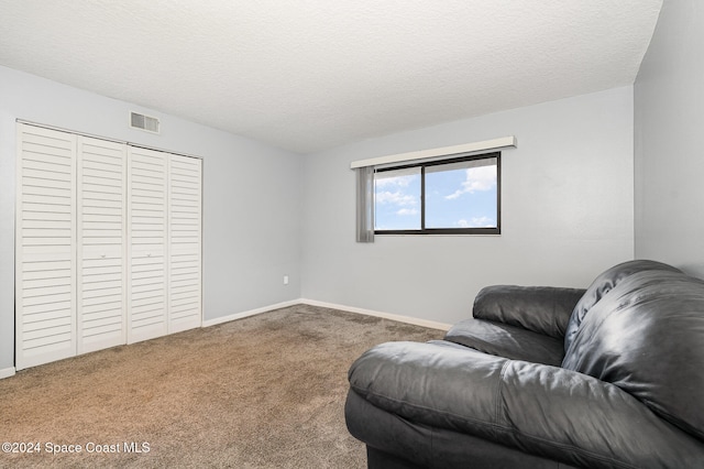 living area with carpet and a textured ceiling