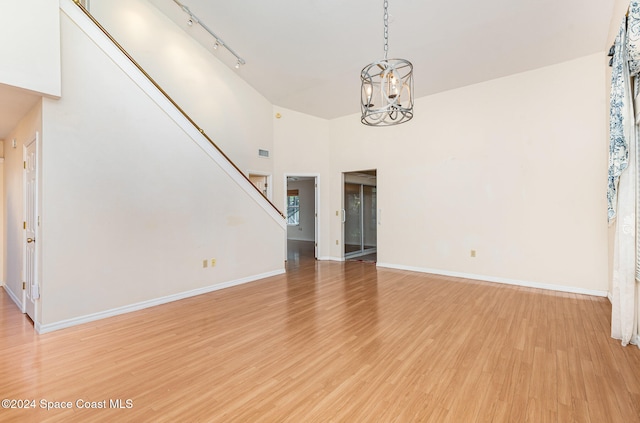 unfurnished living room with a towering ceiling, wood-type flooring, and rail lighting