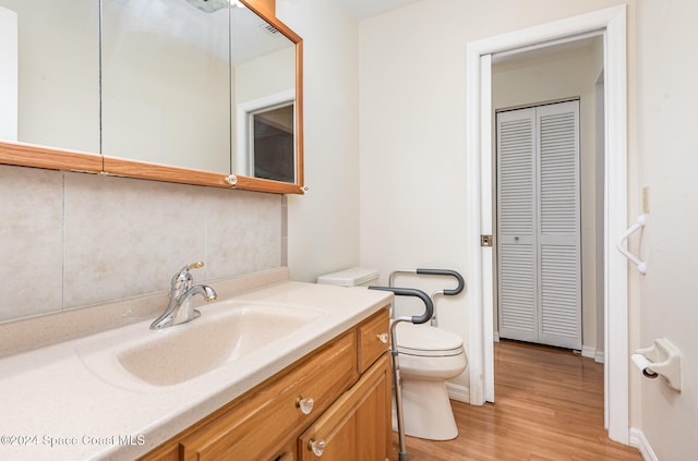 bathroom with toilet, vanity, and hardwood / wood-style floors