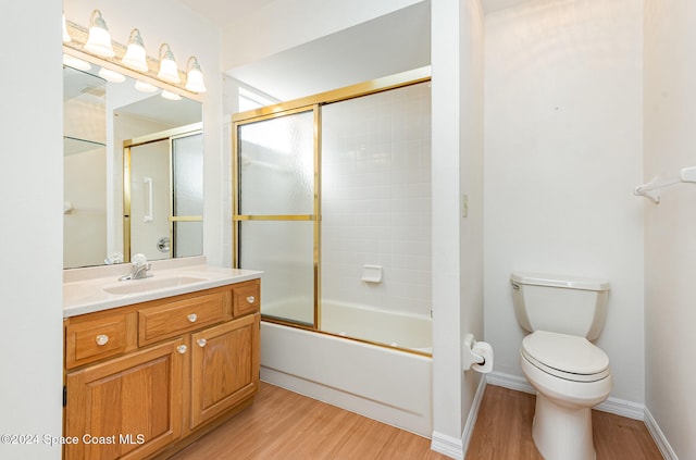 full bathroom with toilet, vanity, wood-type flooring, and shower / bath combination with glass door