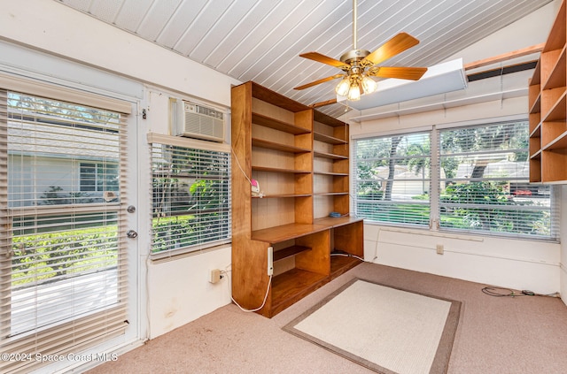 unfurnished office featuring vaulted ceiling with skylight, ceiling fan, carpet flooring, and an AC wall unit